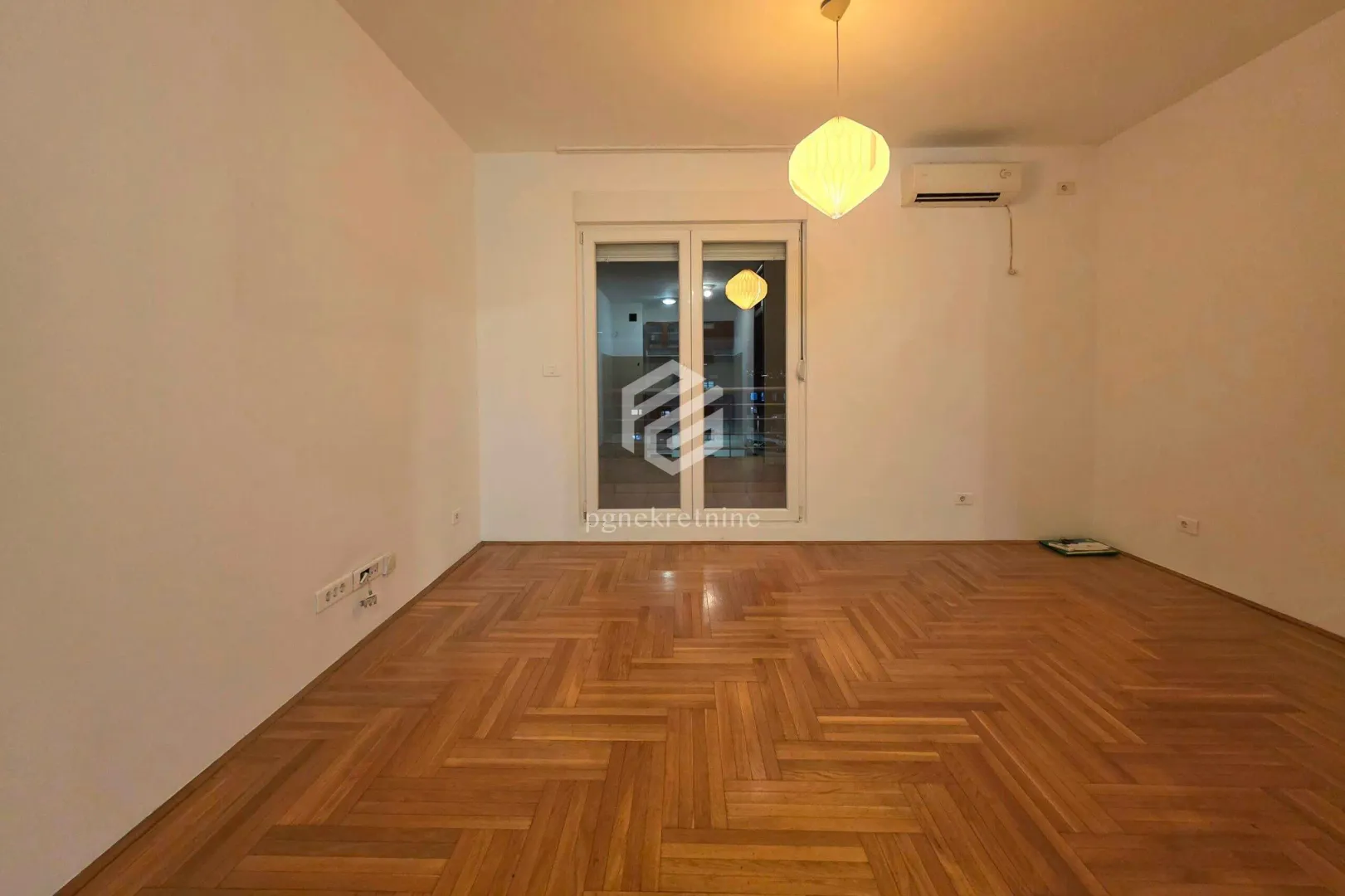Empty room with hardwood parquet flooring and access to the terrace.