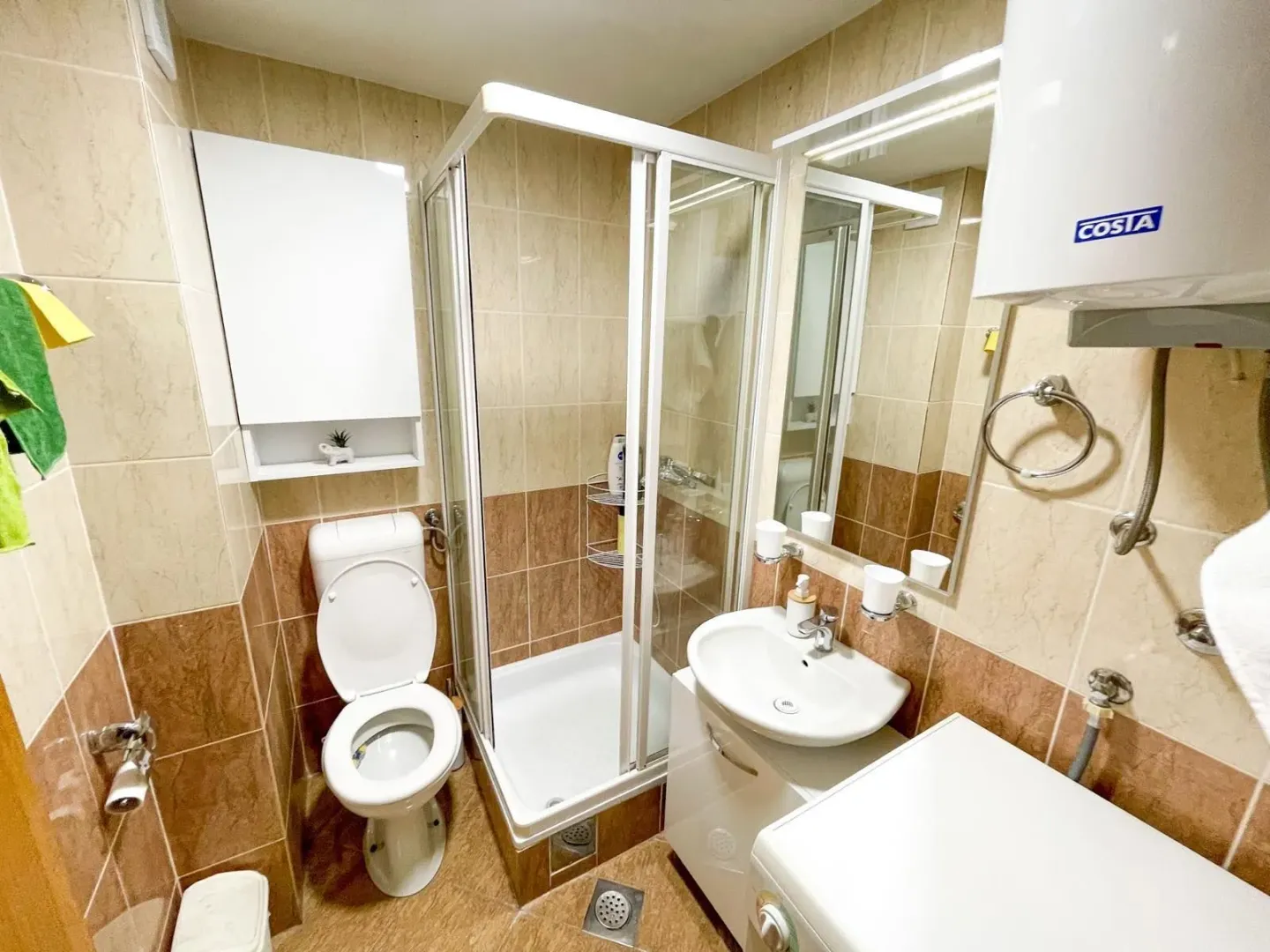 Compactly equipped bathroom with a shower cabin, washbasin, and toilet.