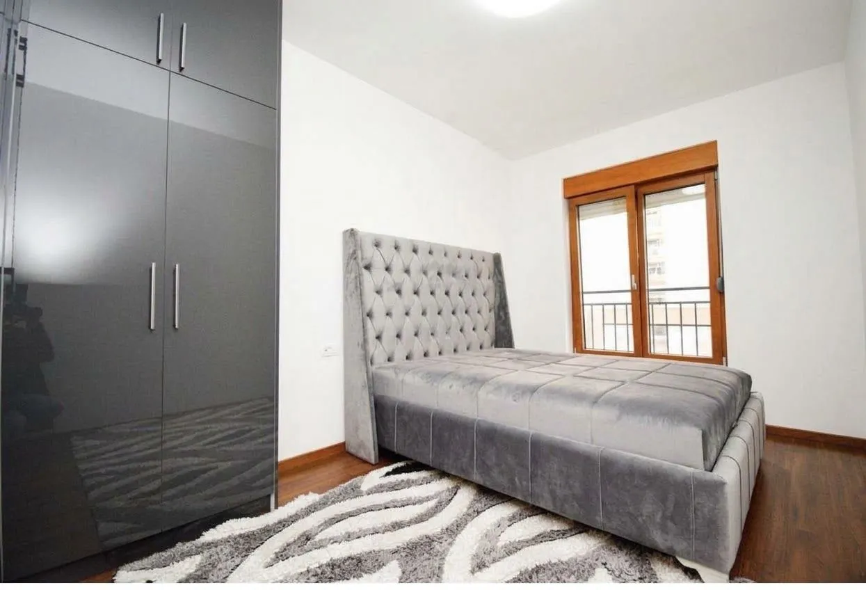 Modern bedroom with a double bed, wardrobe, and window.