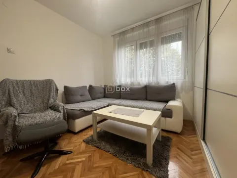 Living room with a sectional sofa, coffee table, and parquet flooring. - image 2