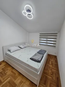 Svjetla spavaća soba sa bračnim krevetom, drvenim parketom i modernom plafonskom rasvjetom. - image 7