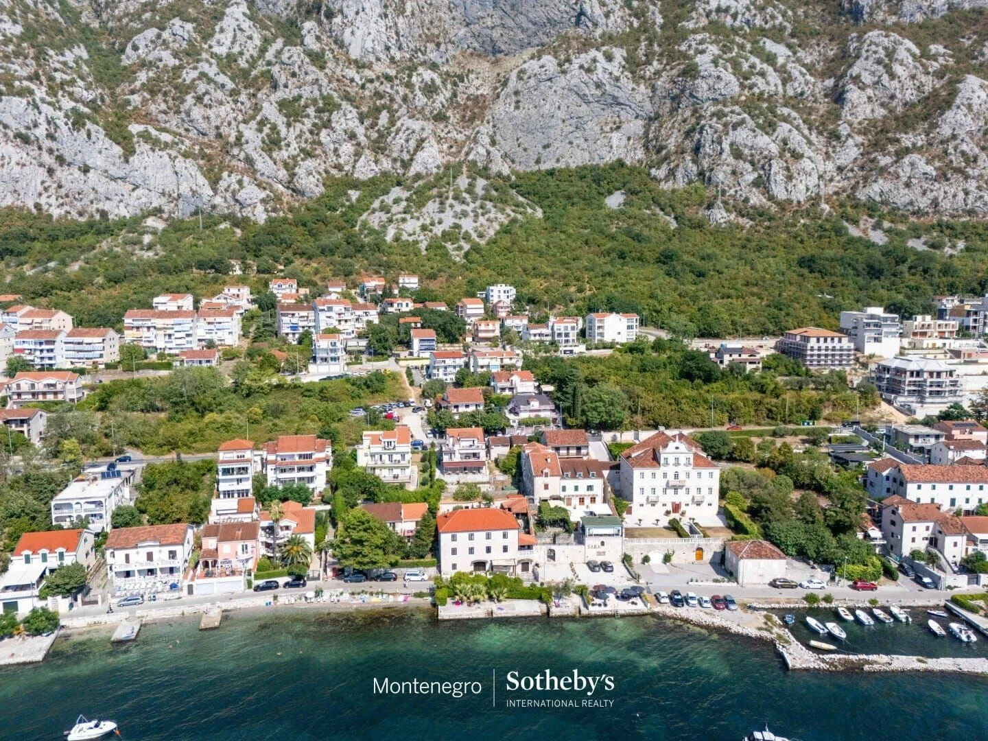 Pogled iz vazduha na priobalno naselje smješteno u podnožju planine.