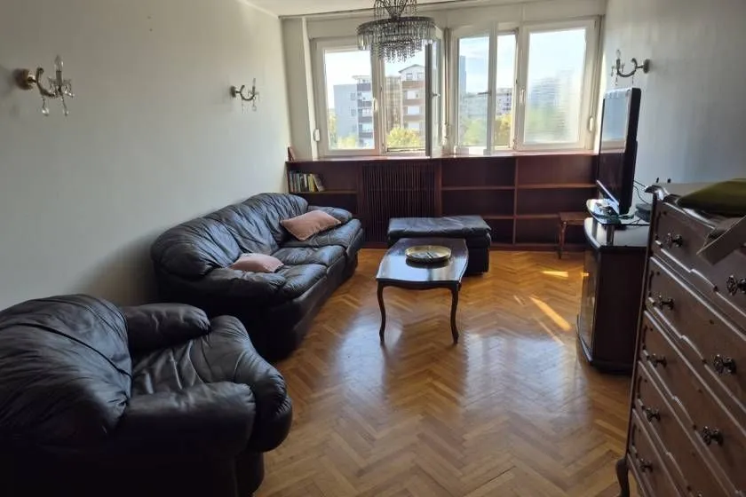 Living room with a seating set, television, and wooden flooring.