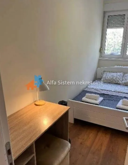 Manja spavaća soba sa krevetom i radnim stolom.