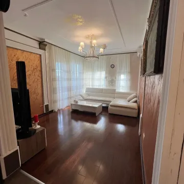 Spacious living room with a white sectional sofa and dark wooden flooring. - image 2