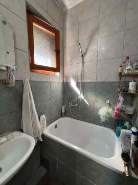 Small bathroom with a bathtub, washbasin, and a window, tiled with ceramic tiles. - image 16