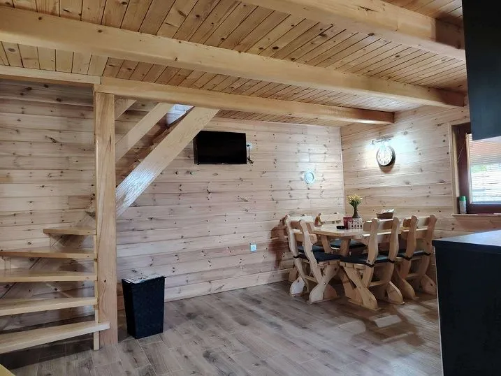 Dnevna soba sa drvenim oblogama, stepeništem i trpezarijskim stolom.
