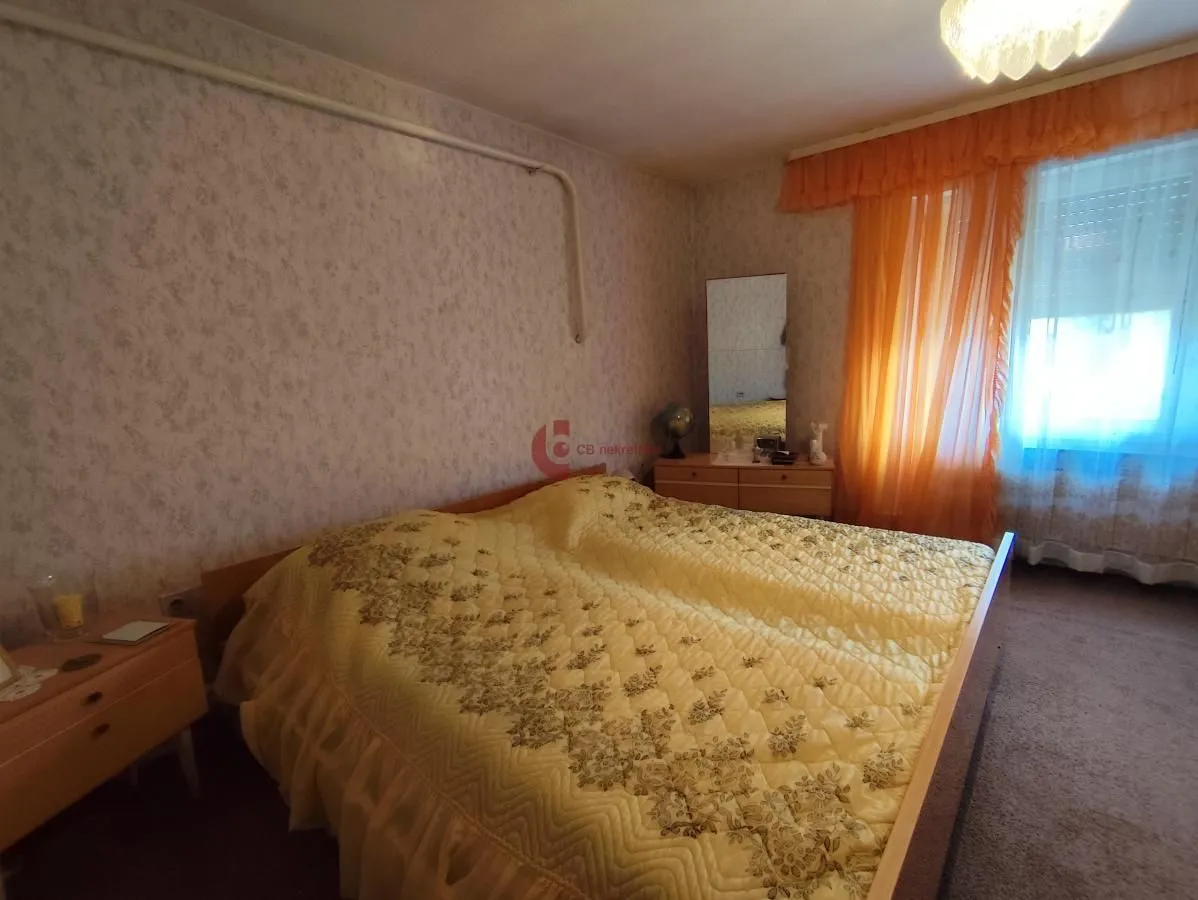 Furnished bedroom with a double bed, dresser, and mirror.