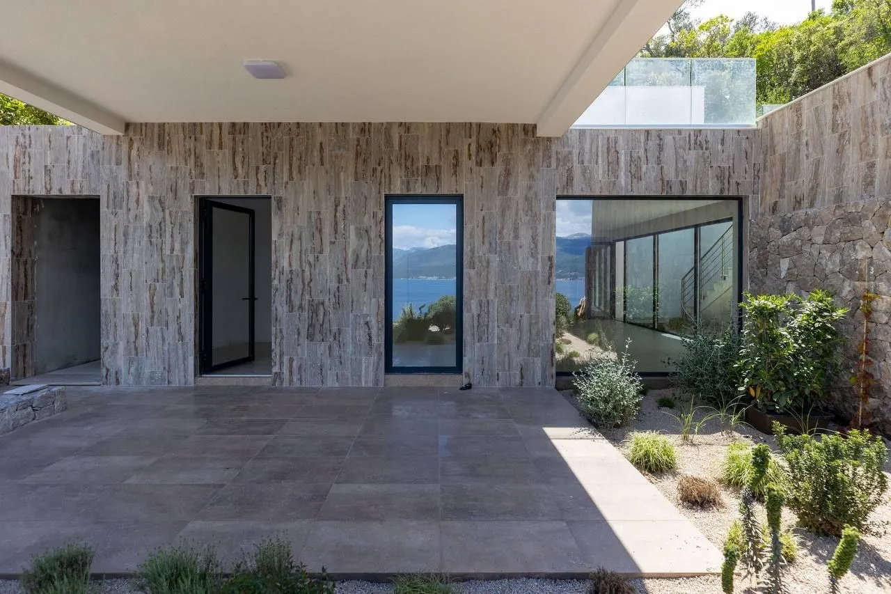 Natkrivena terasa sa popločanim podom i pogledom na more.