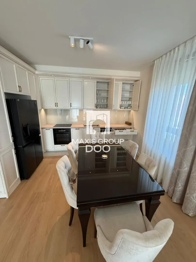 Kitchen with white cabinetry and a black refrigerator, combined with a dining area.