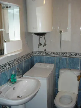 A small bathroom with a sink, washing machine, and boiler. - image 9
