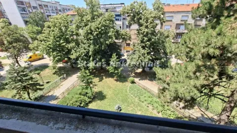 Pogled sa terase na uređeno dvorište i okolne zgrade sa zelenilom. - image 14