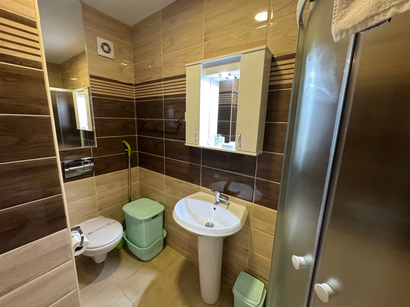 Bathroom with a shower cabin, sink, and beige tiles.