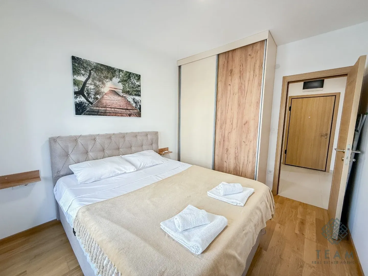 Furnished bedroom with a double bed, wardrobe, and a wall painting.