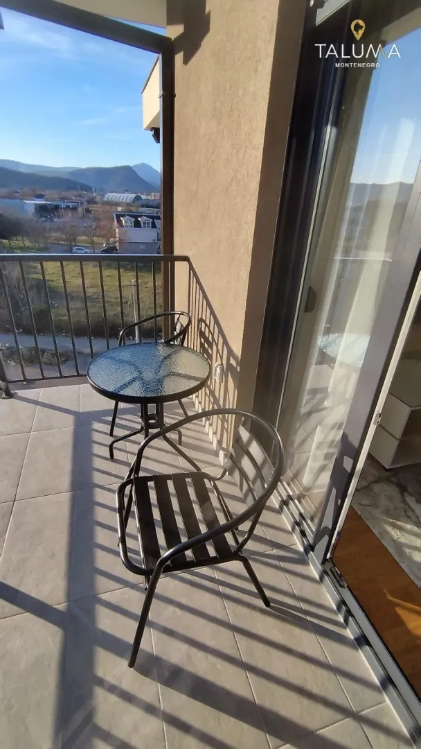 Small balcony with a table, two chairs, and a view of the surroundings.
