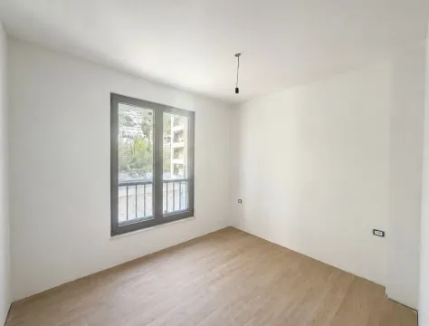 Prazna neopremljena soba sa svijetlim zidovima, drvenim podom i prozorom koji gleda spolja. - image 4