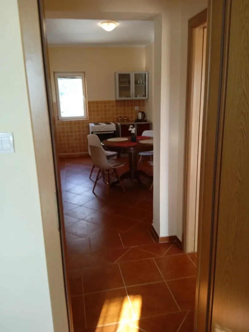 View from the hallway into the kitchen with a dining table and tiled floor.
