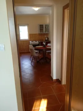 View from the hallway into the kitchen with a dining table and tiled floor. - image 7