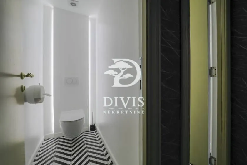 Small bathroom with white walls, a toilet, and black-and-white floor tiles.
