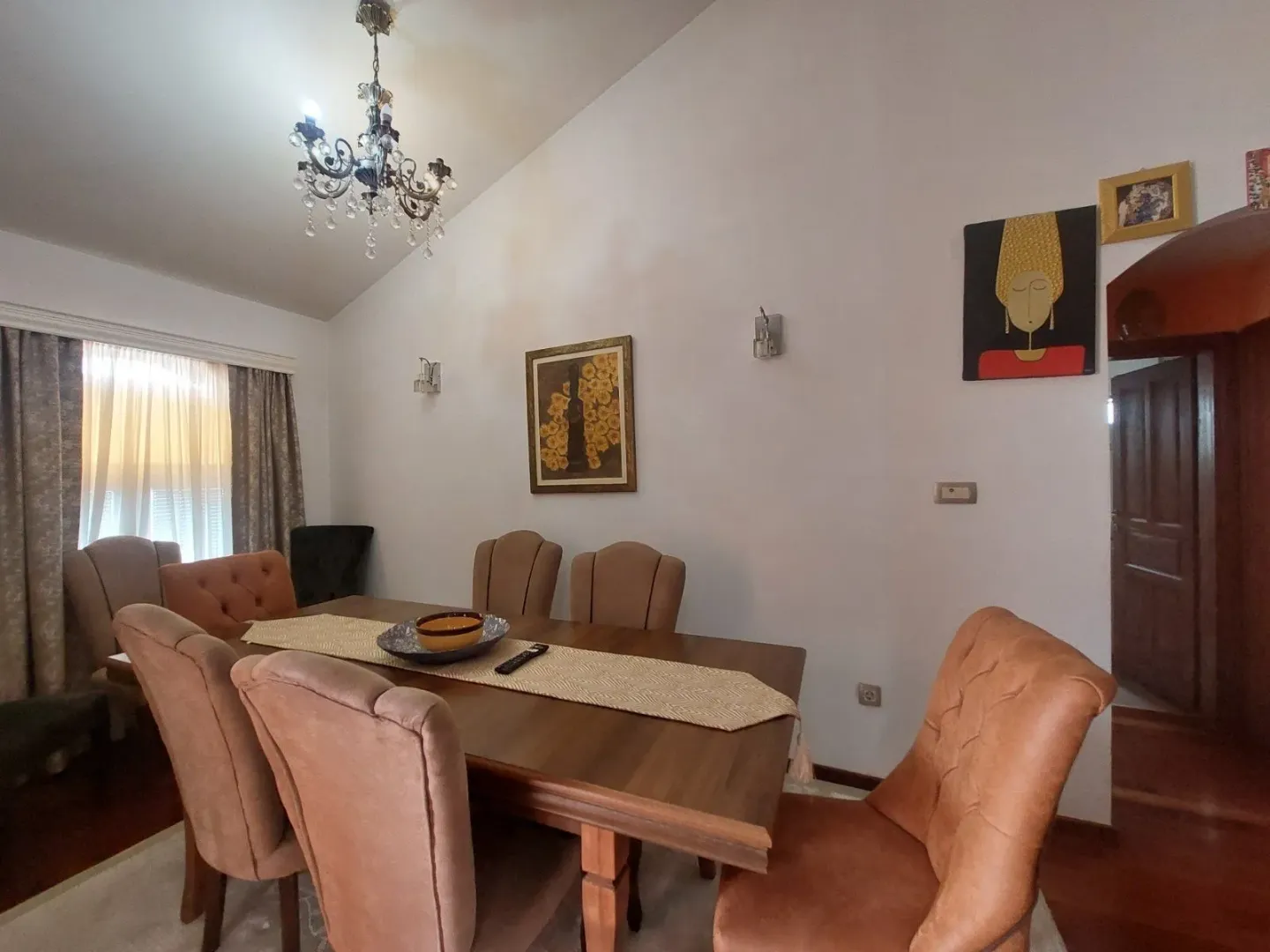 Prostrana trpezarija sa drvenim stolom i tapaciranim stolicama.