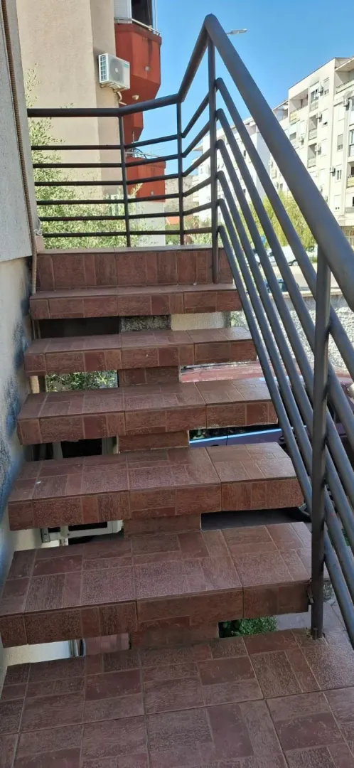 Spoljne stepenice obložene keramičkim pločicama sa metalnom ogradom.