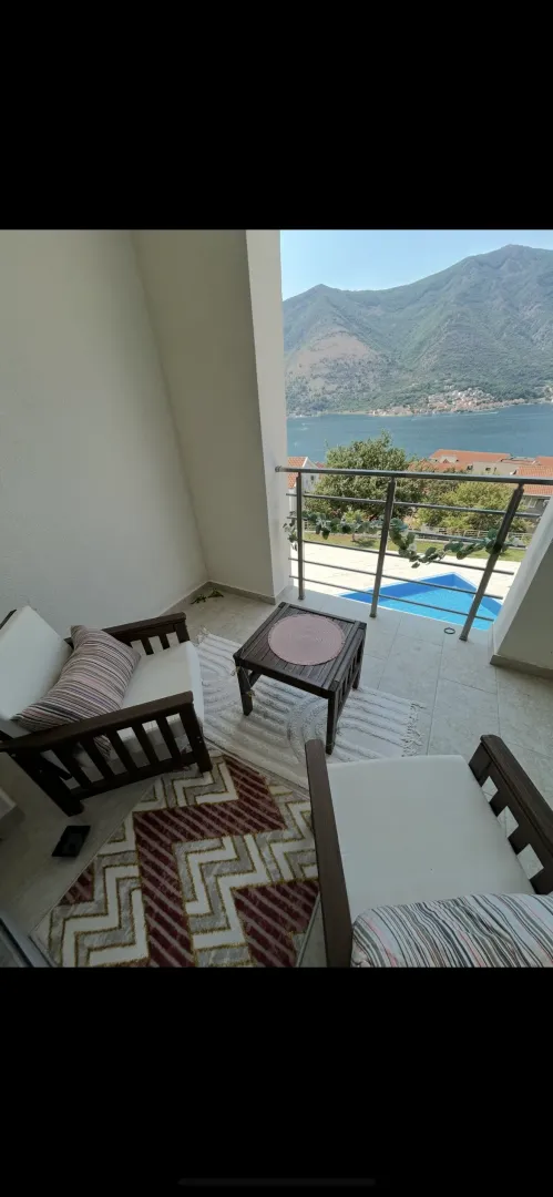 Namješten balkon sa garniturom za sjedenje i pogledom na more i planine.
