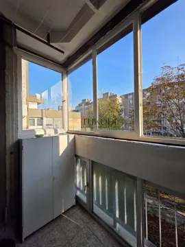 Zastakljeni balkon sa belim ormarićem i pogledom na naselje. - image 4