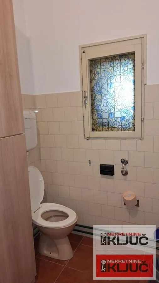 Pogled na kupatilo sa wc šoljom i prozorom sa vitražom.