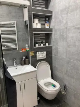 Modernly equipped bathroom with a washbasin, toilet, and built-in shelves. - image 5