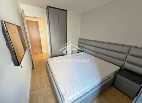 Furnished bedroom with a double bed, wardrobe, and wall-mounted television. - image 13