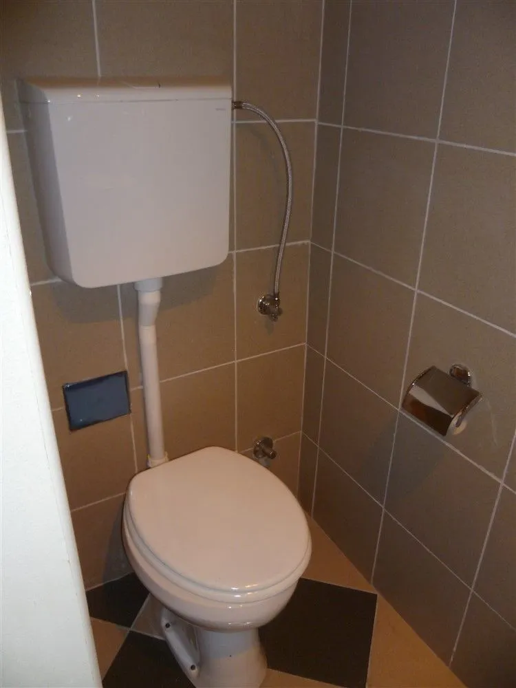 A small toilet with beige tiles.