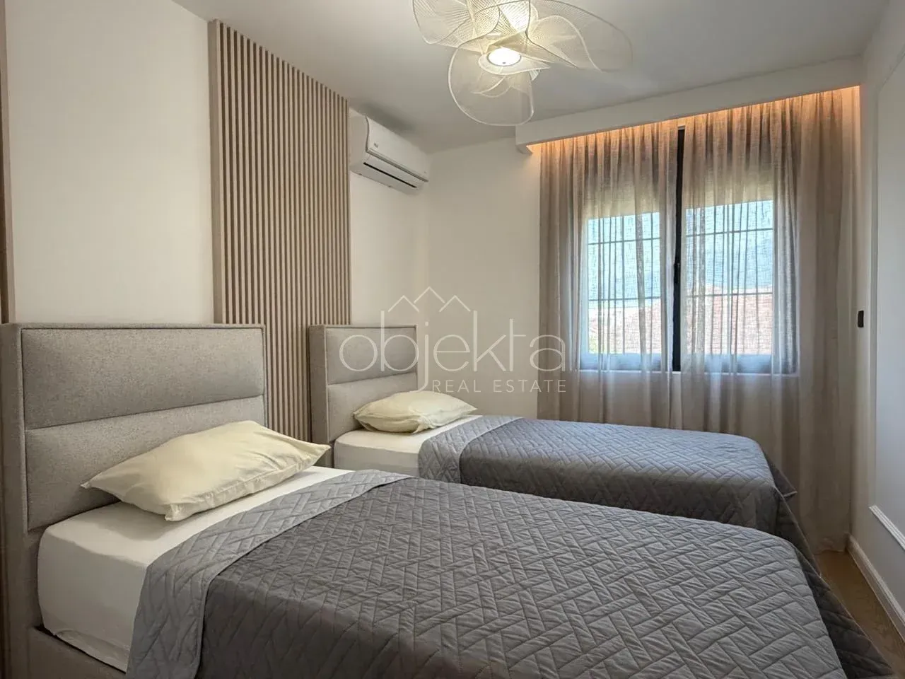 Modern bedroom with two single beds and a decorative wooden wall panel.
