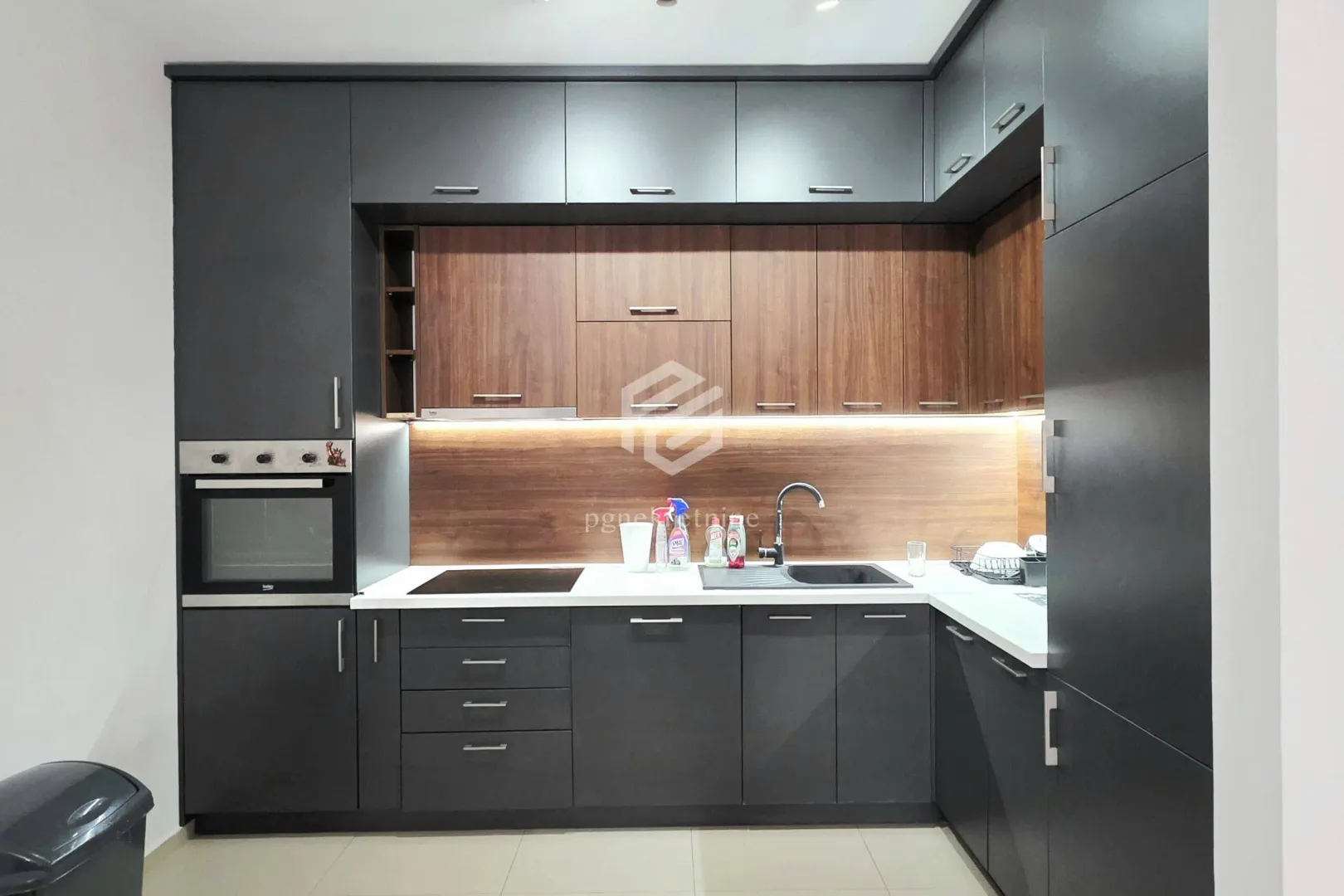Modern dark-toned kitchen with wooden accents and built-in appliances.