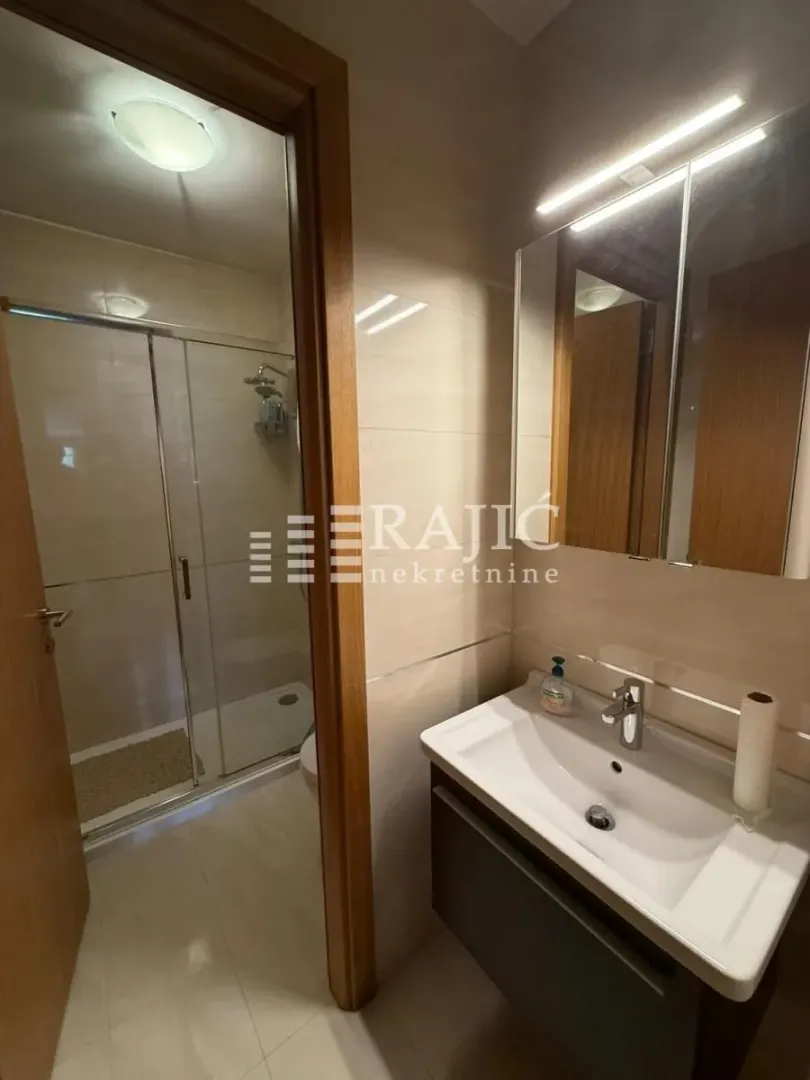 Small bathroom with a shower cabin, washbasin, and mirror.