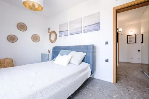 Svjetla spavaća soba sa plavim krevetom i ukrasnim detaljima na zidu. - image 6