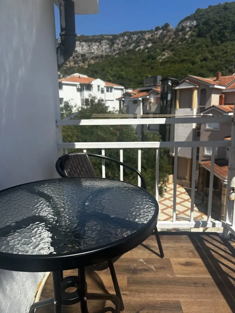 Manji balkon sa stolom, stolicama i pogledom na naselje i brdo.