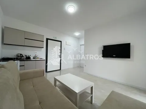 Living room with sofa, television and kitchen units in the background. - image 4