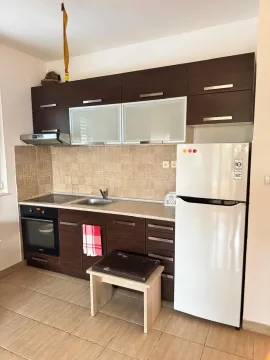 Manja kuhinja sa tamnim drvenim elementima i bijelim frižiderom. - image 3
