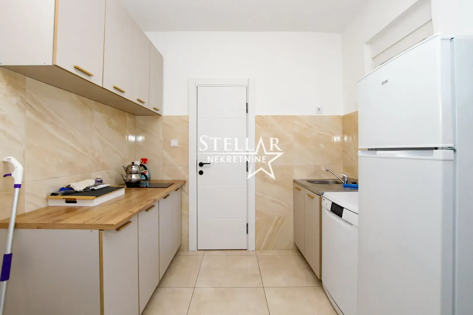 Small kitchen with light-colored cabinets and built-in appliances.