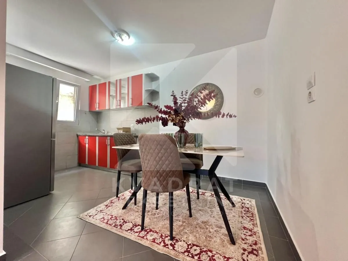 Kitchen with red units and a dining table with chairs.