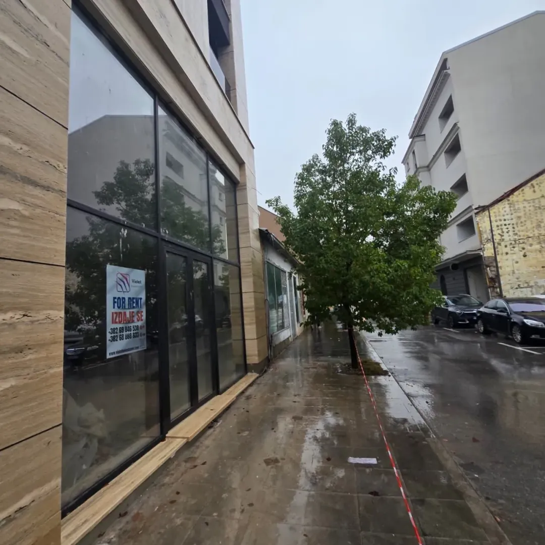 View of the exterior of the building with a large glass shopfront and sidewalk.