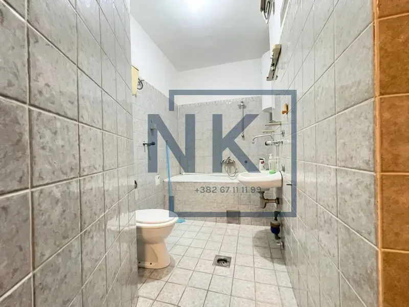 Manje kupatilo obloženo keramičkim pločicama sa kadom, umivaonikom i wc šoljom.