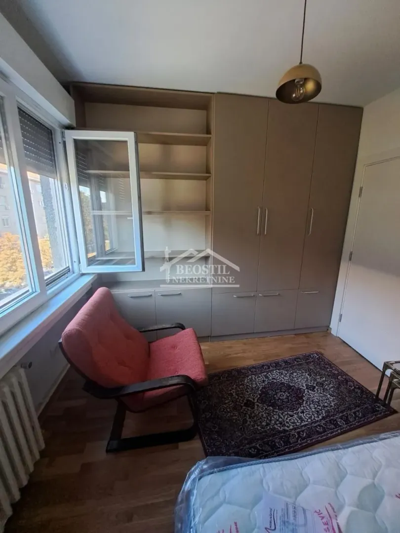 Manja spavaća soba sa ugradnim plakarom, foteljom i prozorom.