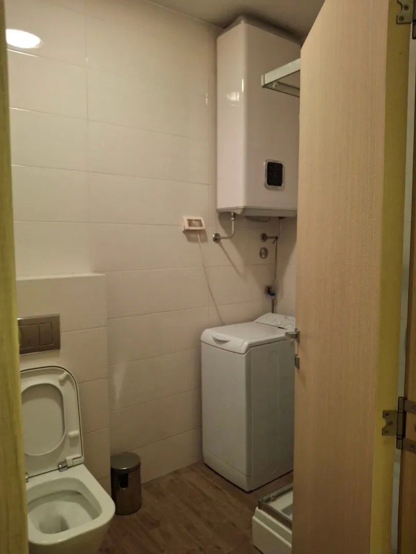 View of a modernly equipped bathroom with sanitary facilities and a washing machine.