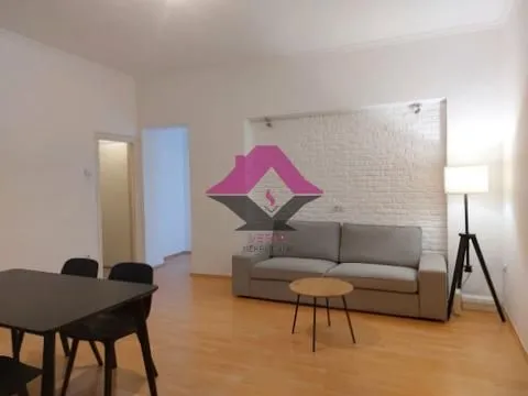 Living room with a sofa, dining table, and decorative brick wall.