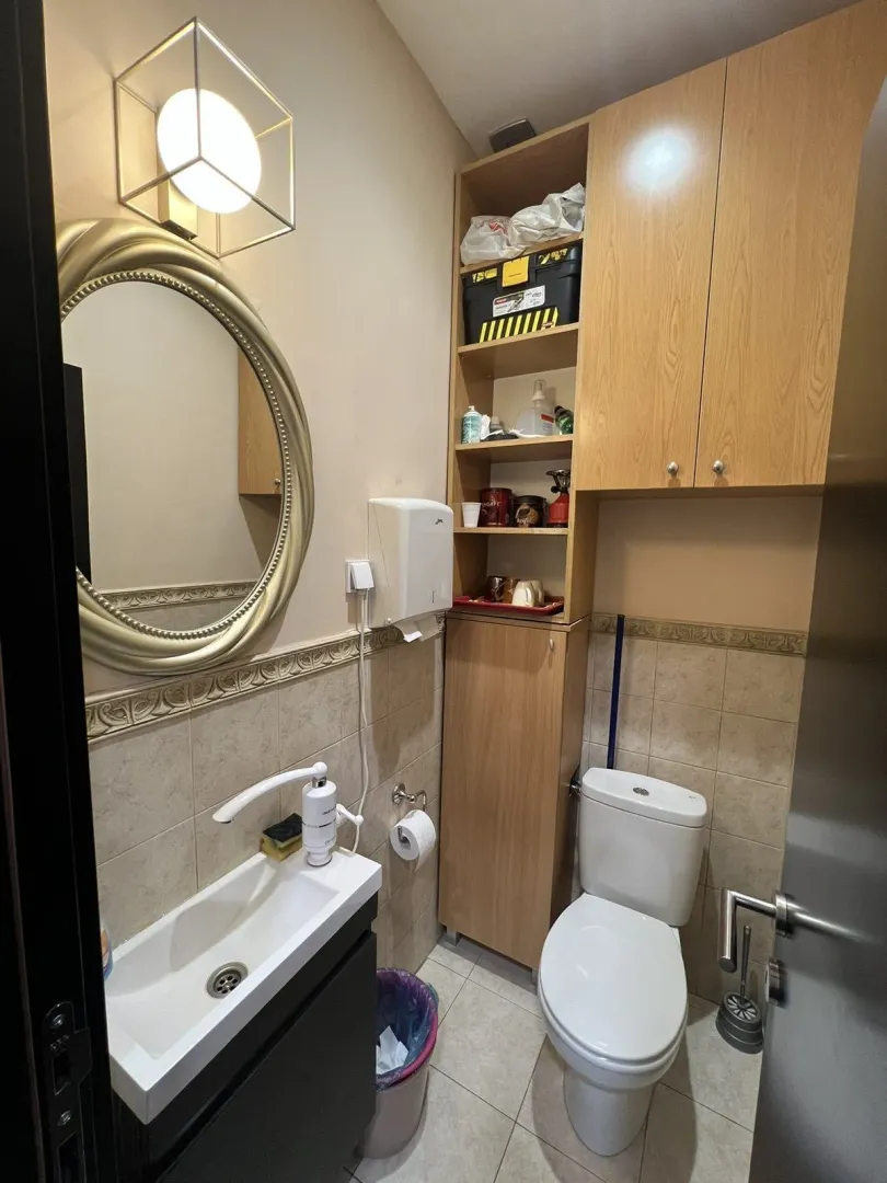 A small functional bathroom with a mirror, sink, and toilet.