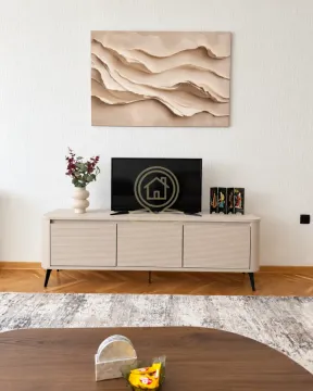 Dnevna soba sa televizorom na komodi i ukrasnim detaljima na zidu. - image 6