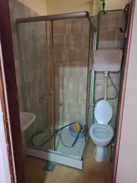 Small bathroom with a shower cabin, toilet, and washbasin. - image 7