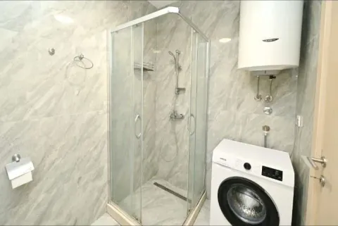 Bathroom with a shower cabin, water heater, and washing machine. - image 8