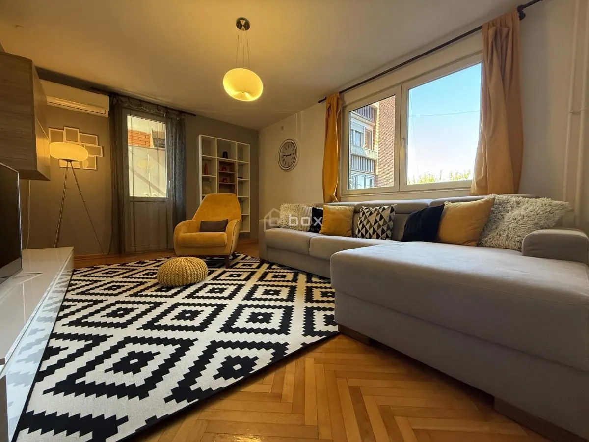 Living room with a sectional sofa, armchair, and a large window.